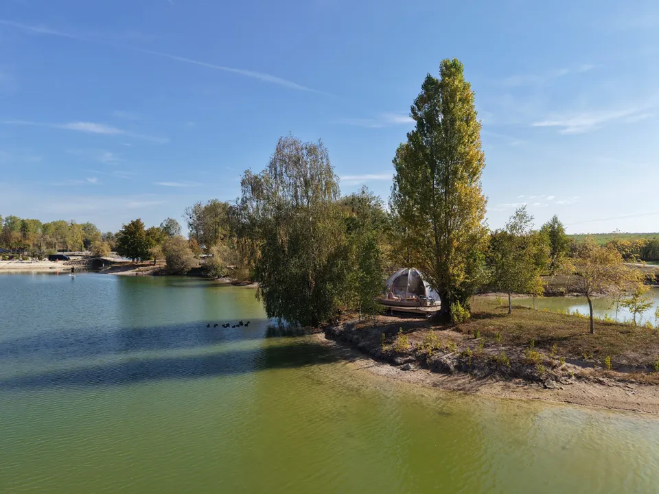 Le Dôme Étoilé sur île, au bord de l'eau, à l'ombre d'un grand peuplier.