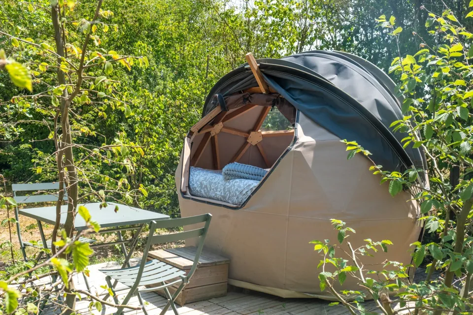 La bulle et sa terrasse aménagée, nichée dans la verdure.