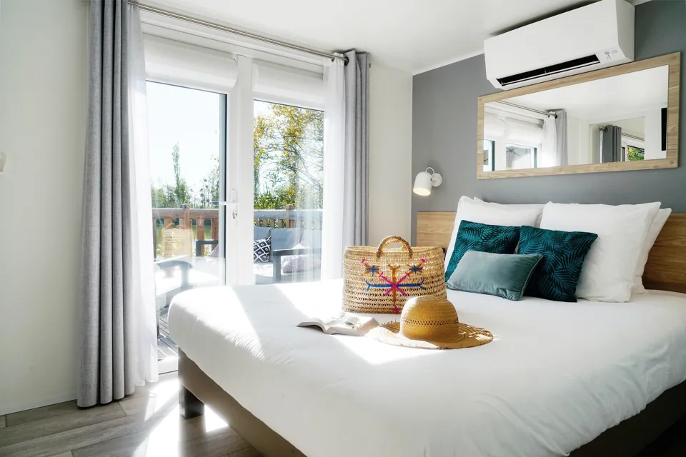 Une chambre, ouverte sur la terrasse et l'étang.