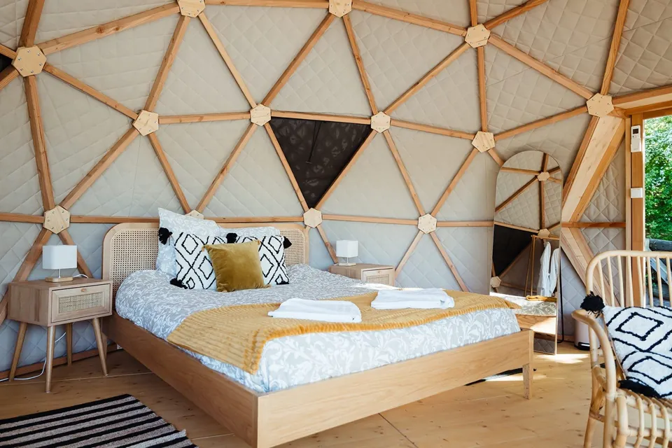 La chambre et son grand lit, sous la charpente en bois du dôme.