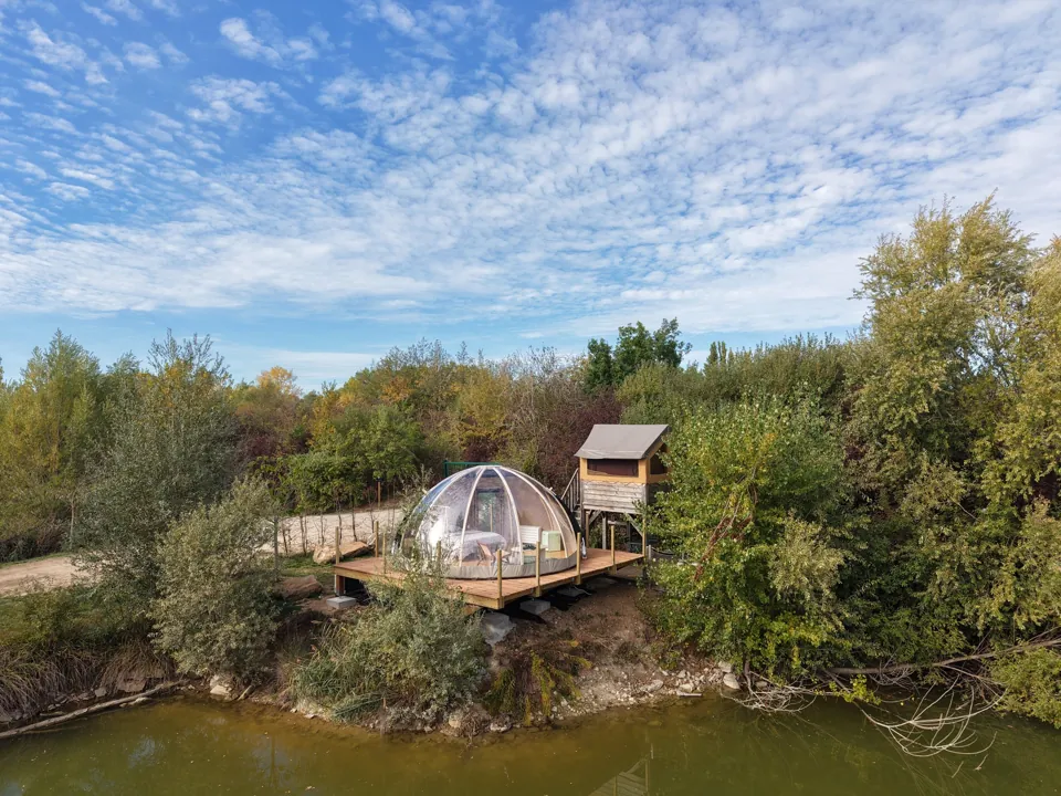 Le dôme et sa cabane sur pilotis, réunis sur un espace privé au bord de l'étang.