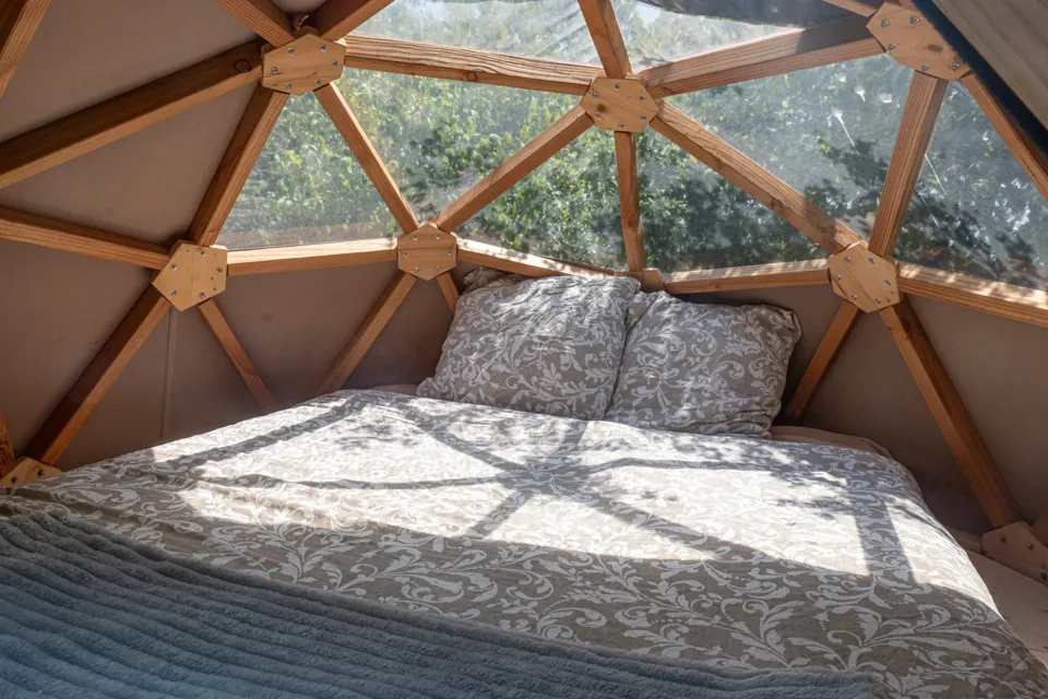 Le lit double sous la voûte transparente, face aux arbres.