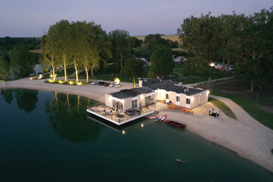 La Villa Carpe Diem et sa terrasse sur pilotis au-dessus de l'eau, à la tombée de la nuit.