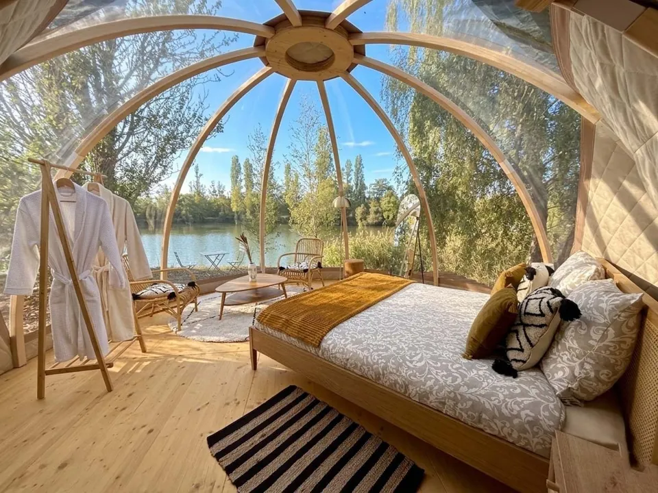 L'intérieur du dôme : grand lit, coin salon et vue panoramique sur l'étang.