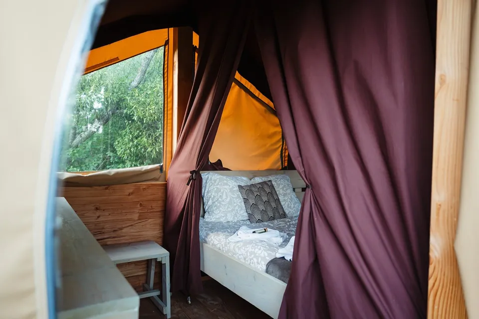 Le lit double, niché derrière ses rideaux.
