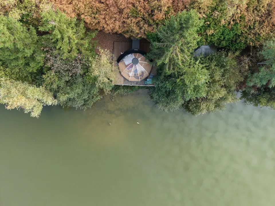 Le Dôme Étoilé et sa terrasse au bord de l'eau, vus du ciel.